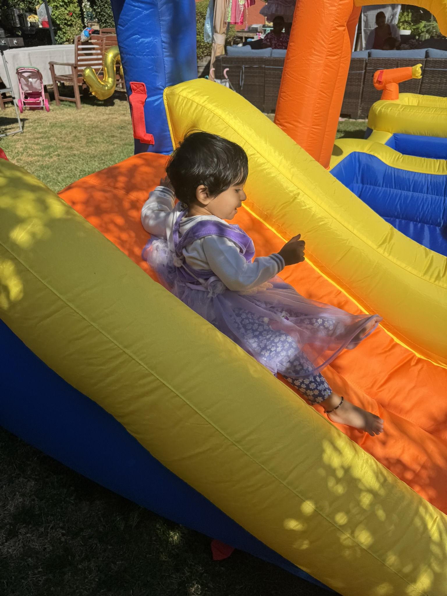 Child in princess dress on bounce house slide